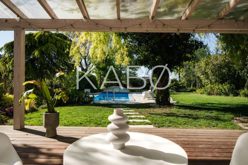 Dom medzi stromami: Nadčasová architektúra v Cabaj-Čápore - Záhradná terasa rodinného domu v Cabaji-Čápore s výhľadom na bazén a zeleň.