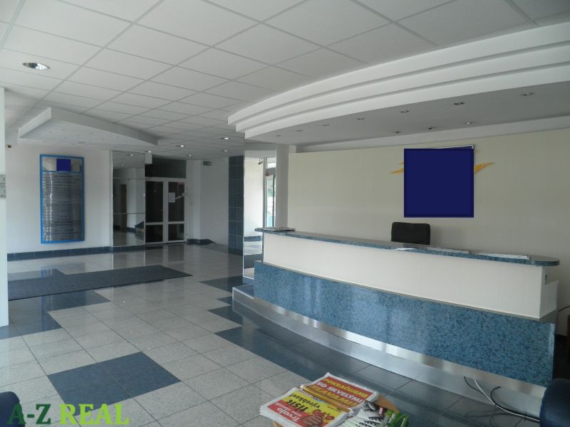 Prenájom kancelárskych priestorov  Drieňová ul., 209 m2 - 600 m2 - Recepcia v kanceláriách s dlažbou, stropnými panelmi a časopismi na stole.