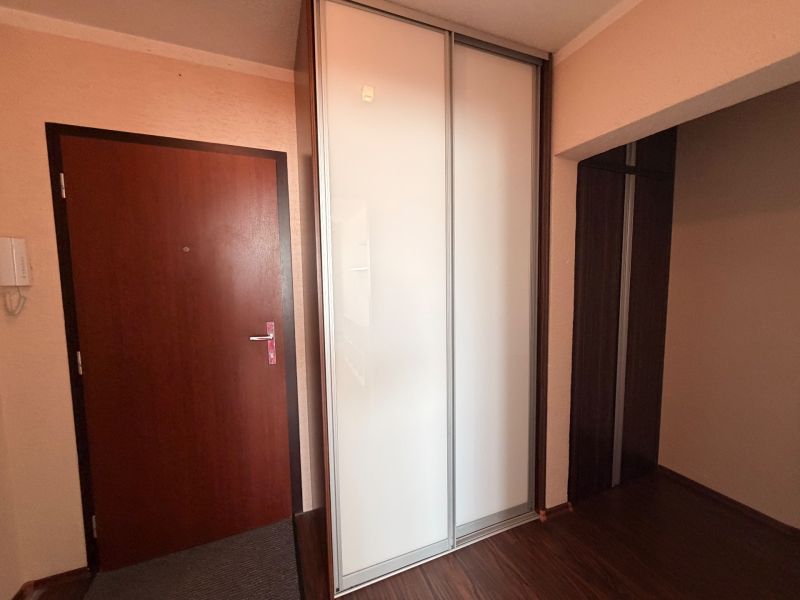 NOVINKA!!! Priestranný 3-izbový byt, 72 m² | Karpatská, Sásová - Predsieň v 3-izbovom byte s bielou šatníkovou skriňou a podlahou s dreveným dekorom.