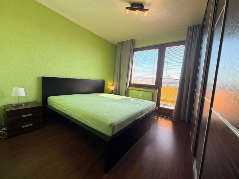 NOVINKA!!! Priestranný 3-izbový byt, 72 m² | Karpatská, Sásová - Spálňa v 3-izbovom byte s podlahou s dreveným dekorom a zelenými stenami.