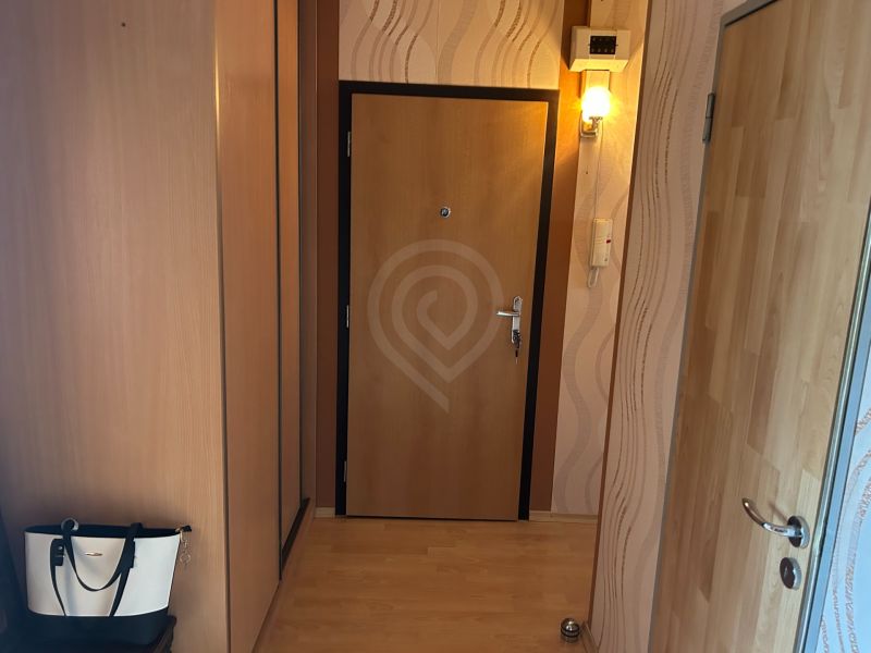 NA PREDAJ PRIESTRANNÝ 3-IZBOVÝ BYT | 67 m² | LODŽIA | 4. POSCHODIE - Chodba v 3-izbovom byte s podlahou s dreveným dekorom a stenovou lampou.