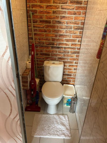NA PREDAJ PRIESTRANNÝ 3-IZBOVÝ BYT | 67 m² | LODŽIA | 4. POSCHODIE - Kúpeľňa v 3-izbovom byte s toaletou, tehlovým vzorom a čistiacimi prostriedkami.