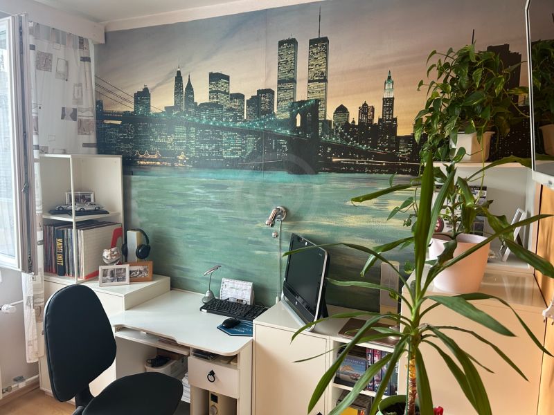 NA PREDAJ PRIESTRANNÝ 3-IZBOVÝ BYT | 67 m² | LODŽIA | 4. POSCHODIE - Pracovný kútik so stolom, rastlinami a dekoratívnou tapetou v 3-izbovom byte.