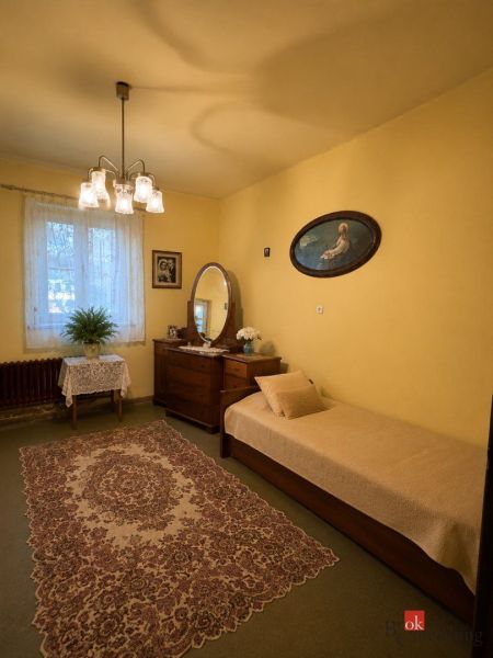 NA PREDAJ - Rodinný dom - Banská Bystrica - CENTRUM - Izba v rodinnom dome s kobercovou podlahou, žltými stenami, posteľou a zrkadlom.