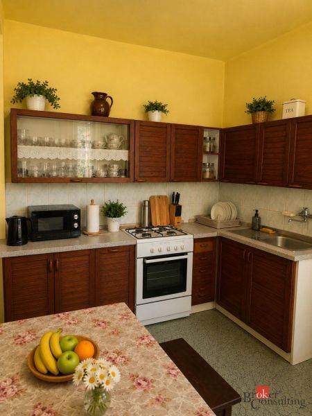 NA PREDAJ - Rodinný dom - Banská Bystrica - CENTRUM - Kuchyňa rodinného domu s drevenými skriňami, stolom a dekoráciami.