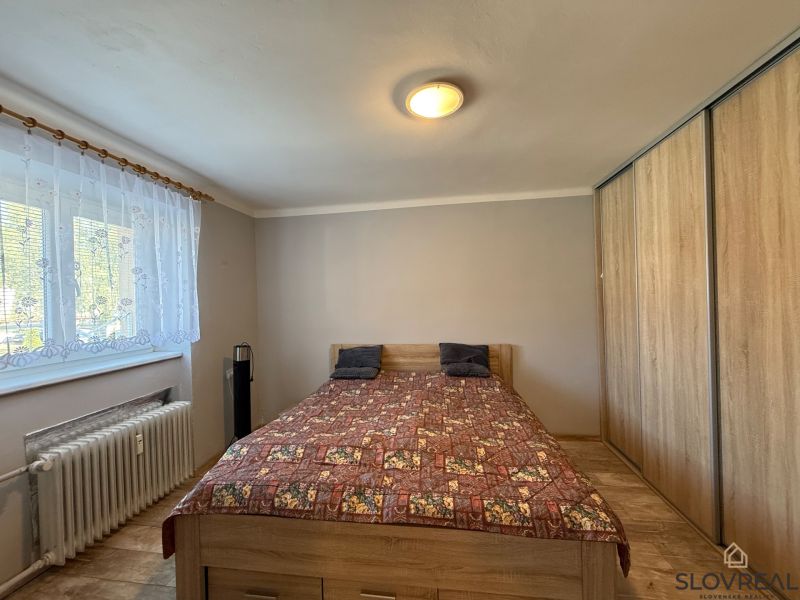 Na predaj 3 byt Žiar nad Hronom, 75m2 - Spálňa v 3-izbovom byte s posteľou, vstavanou skriňou a podlahou s dreveným dekorom.