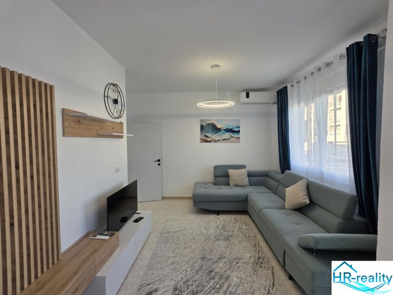 Albánsko, Durres - zariadený apartmán len 100m od mora a pláže - Obývacia izba v 2-izbovom byte so sedačkou, televízorom a dekorom z dreva.