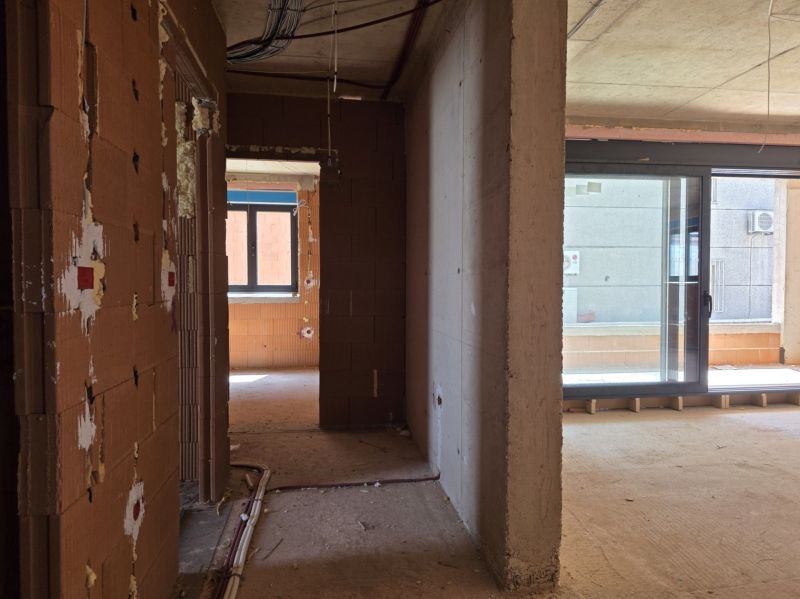 CHORVÁTSKO - Apartmány 2.rad od mora - SRIMA, VODICE - Nedokončený interiér 3-izbového bytu s veľkými sklenenými dverami a murivom.