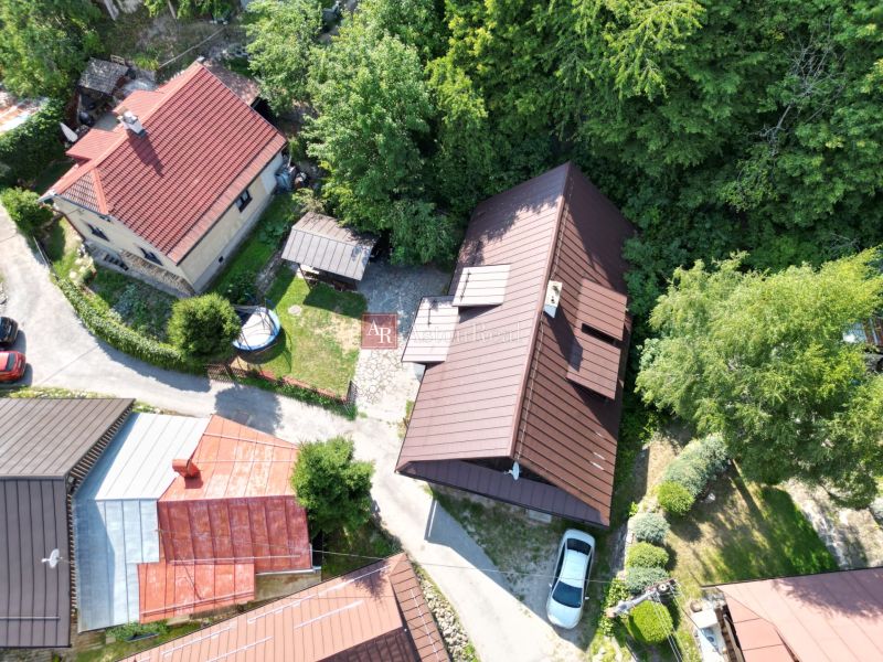 Predaj: Štýlová chalupa v srdci Španej Doliny miesto s atmosférou  - Letecký pohľad na chatu v Španej Doline pri Banskej Bystrici obklopenú zeleňou a domami.