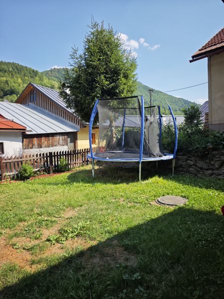 Predaj: Štýlová chalupa v srdci Španej Doliny miesto s atmosférou  - Trampolína pri chate v Španej Doline, obklopená trávou a stromami v pozadí.