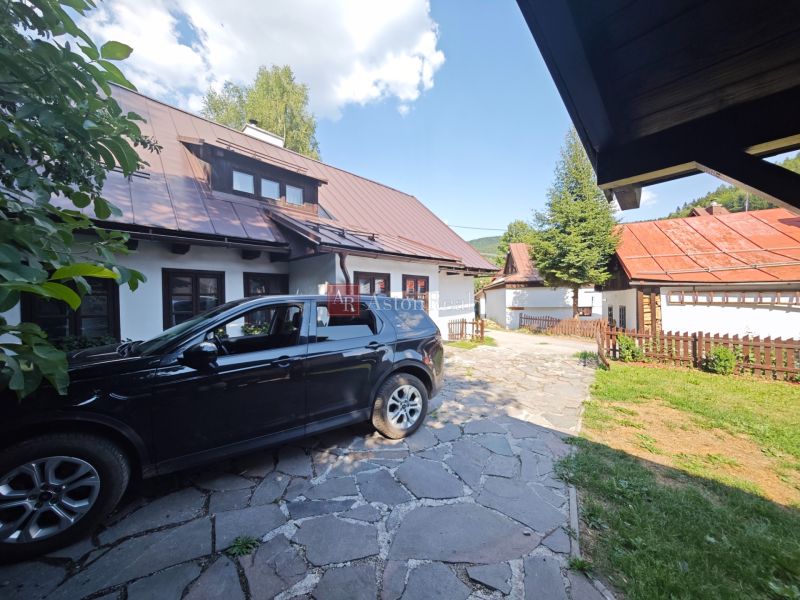 Predaj: Štýlová chalupa v srdci Španej Doliny miesto s atmosférou  - Auto zaparkované pri chate v Španej Doline, s viditeľnými strechami a plotom.