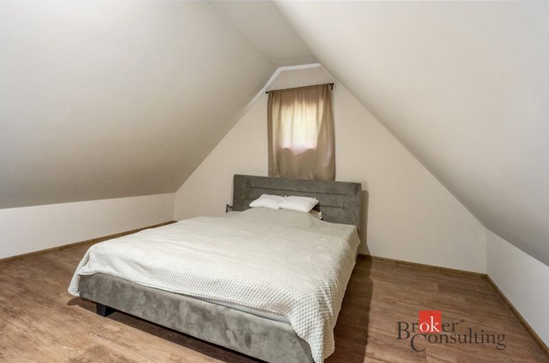 Chata na samote na predaj, Píla, Žarnovica - Podkrovná spálňa na chate s posteľou a podlahou s dreveným dekorom.
