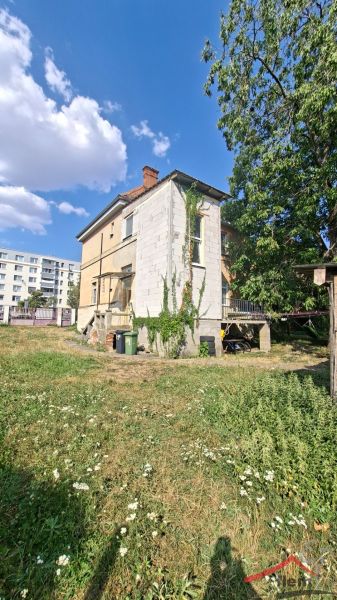 Dom na predaj Vráble, pozemok 1179 m2 - Rodinný dom na Levickej ulici vo Vrábľoch s bohatou zeleňou a tehlovou strechou.