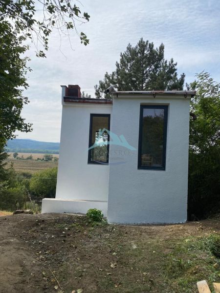 Vaša nová oáza pokoja s investičným potenciálom v Šahách - Malá chata v Šahách, obklopená stromami a krásnou prírodou.