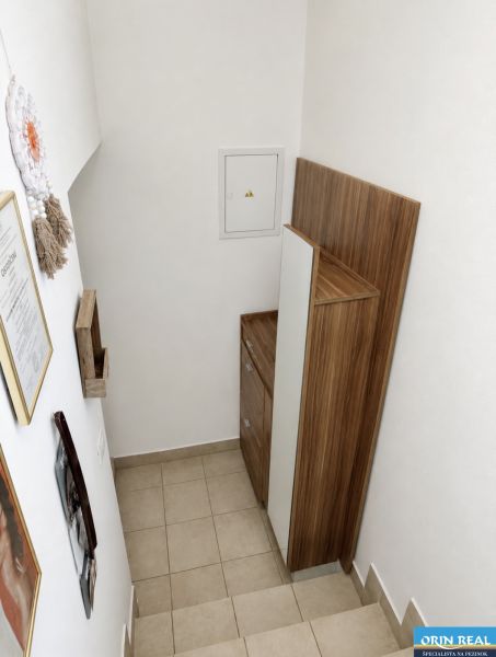 Krásny priestranný klimatizovaný 1izbový byt s terasou 66m2 - Schodisko s úložným priestorom v 1-izbovom byte, biela stena, drevený dekor.