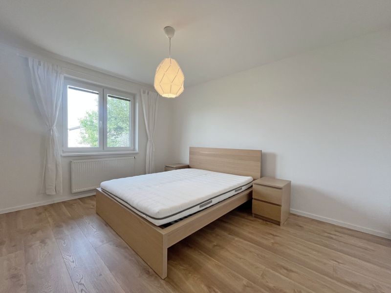 Rodinný dom v obci Láb, kľudná slepá ulica - Spálňa s posteľou, nočnými stolíkmi a podlahou s dreveným dekorom v rodinnom dome.