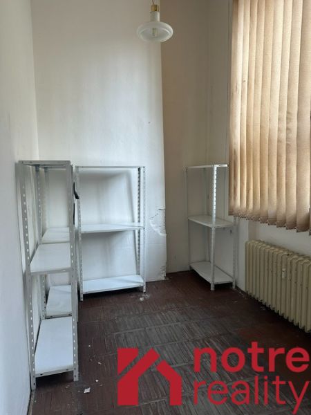 Na prenájom reprezentatívne nebytové priestory v centre mesta Lučenec - Kancelária s regálmi, radiátorom a závesmi, podlaha s dreveným dekorom.