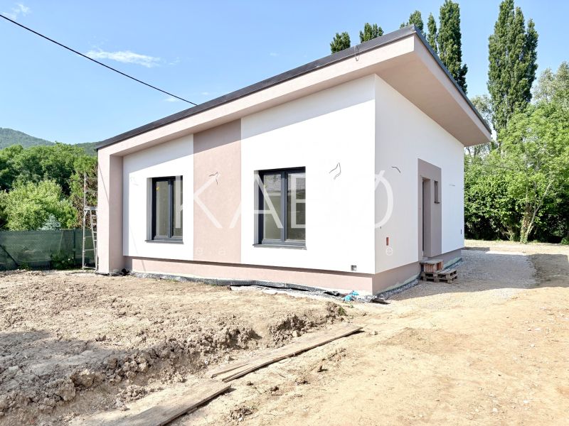 Novostavba moderného 4i rodinného domu v Štitároch - Exteriér rodinného domu v Štitároch s jednoduchou fasádou a oknami na svahovitom teréne.