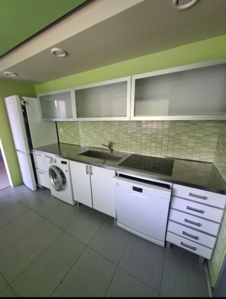 Prenajom moderného 3izb bytu na SNP ul - Kuchyňa v 3-izbovom byte s bielymi skrinkami a zelenými obkladmi.