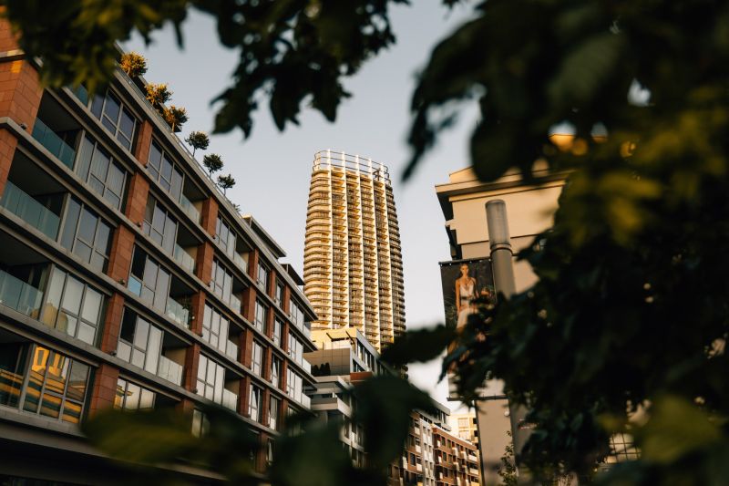 EUROVEA TOWER - Penthouse 4-izbový s výhľadom na downtown , 44.p - Výšková budova v pozadí ulice so zeleňou a bytovými jednotkami v Bratislave.