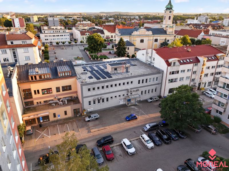 Obchodné priestory na námestí Topoľčany  PRENÁJOM - Výhľad na M.R. Štefánika v Topoľčanoch s obchodnými priestormi a kostolom v pozadí.