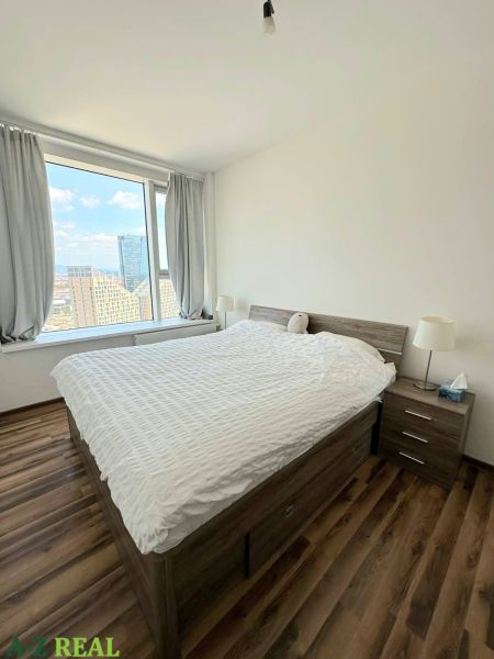 Na prenájom luxusný 3 izb. byt s garážou v Panorama City, Staré Mesto. - Izba s veľkým oknom, posteľou a podlahou s dreveným dekorom v 3-izbovom byte.