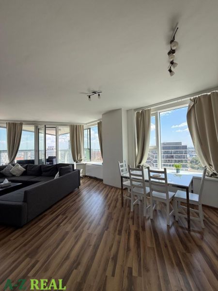 Na prenájom luxusný 3 izb. byt s garážou v Panorama City, Staré Mesto. - Obývacia izba v 3-izbovom byte s podlahou s dreveným dekorom a veľkými oknami.