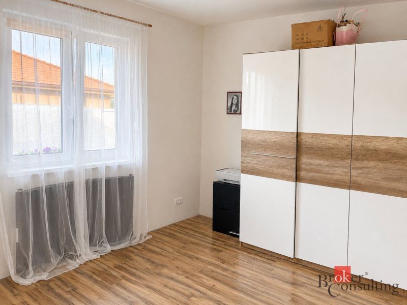 Predaj bungalovu - drevodom - Biela skriňa s dreveným dekorom a závesmi v izbe rodinného domu.