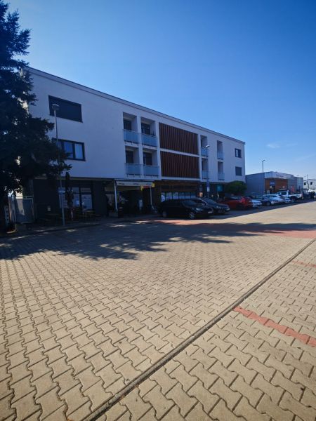 Moderný 2- izbový byt na prenájom , Rohožník - Budova na Senickej ulici v Rohožníku s parkovacími miestami v popredí.