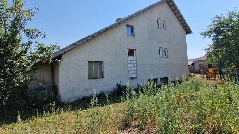 Na predaj dvojpodlažný rodinný dom v obci Kazimír, okres Trebišov - Rodinný dom na ulici Biela v Kazimíri obklopený zeleňou pod modrou oblohou.