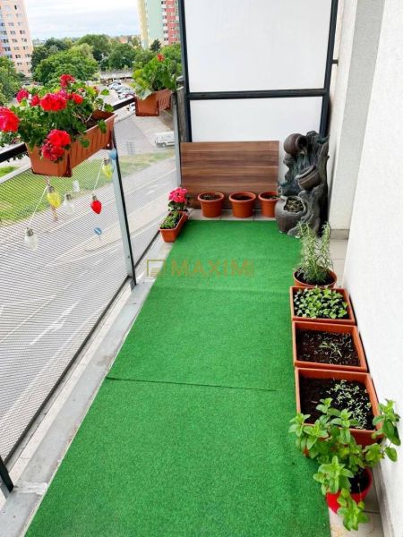 Veľký, slnečný a priestranný 3-izbový byt  - Balkón s kvetináčmi, umelým trávnikom a výhľadom na Vrakuňskú cestu v Bratislave.