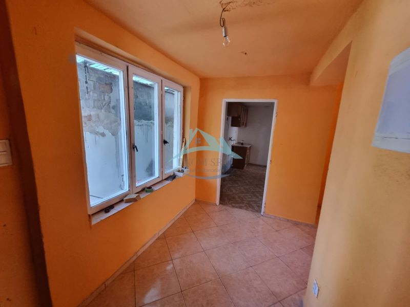 Dvojgeneračný rodinný dom s obrovským potenciálom v Šahách - Oranžovo vymalovaná chodba s oknami a dlažbou, vedúca do ďalšej miestnosti v rodinnom dome.