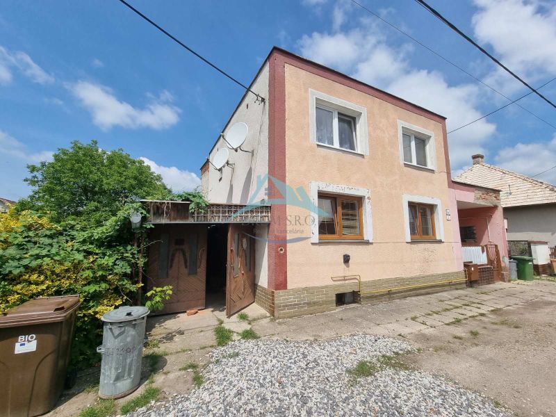 Dvojgeneračný rodinný dom s obrovským potenciálom v Šahách - Rodinný dom na Šípošovej ulici v Šahách obklopený zeleňou a kontajnermi.