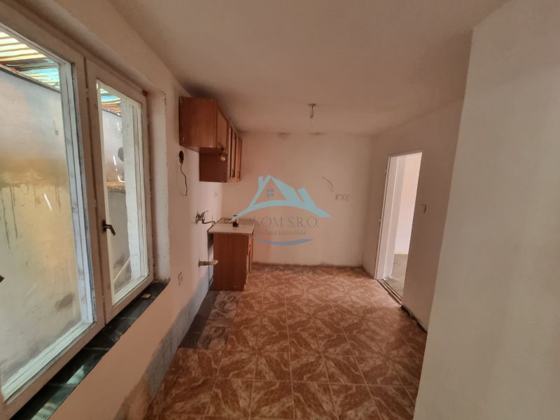 Dvojgeneračný rodinný dom s obrovským potenciálom v Šahách - Kuchyňa v rodinnom dome s oknom a podlahou s dreveným dekorom.