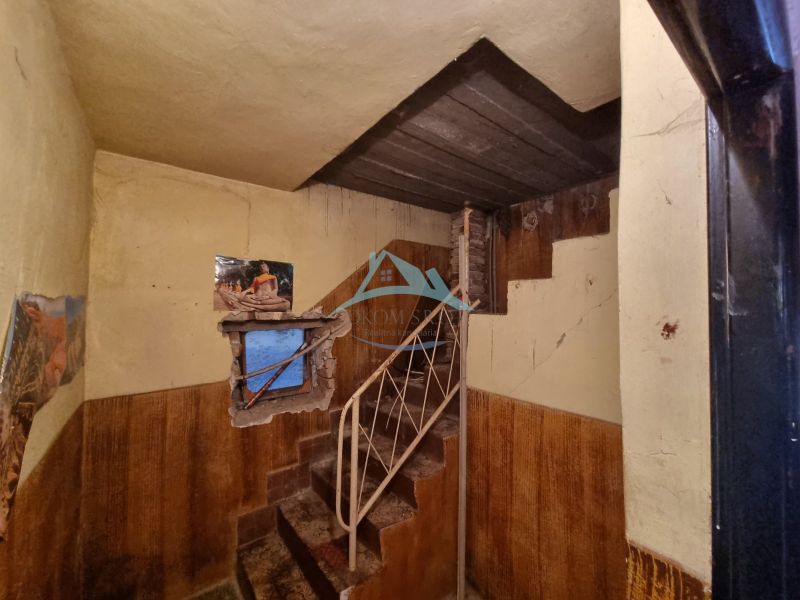 Dvojgeneračný rodinný dom s obrovským potenciálom v Šahách - Interiér rodinného domu s kovovým schodiskom, ošúchanými stenami a oknom s tapetou.