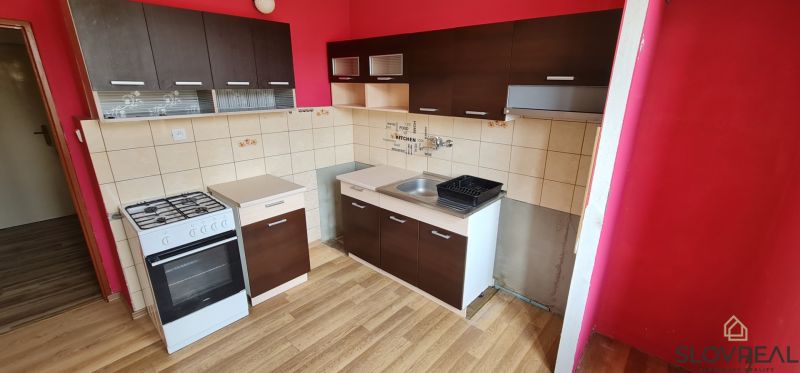 Na predaj 2i byt Levice, 48m2 - Kuchyňa v 2-izbovom byte s podlahou s dreveným dekorom a červenými stenami.