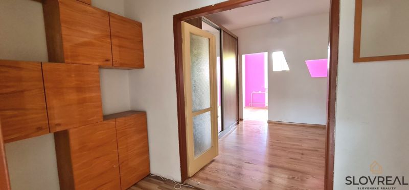 Na predaj 2i byt Levice, 48m2 - Interiér 2-izbového bytu s podlahou s dreveným dekorom a vstavanou skriňou.