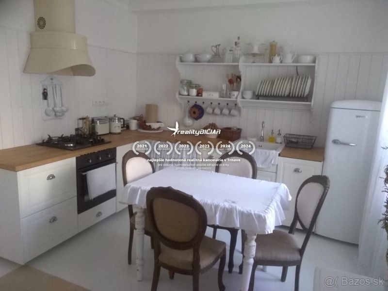 Priestranný 2-izbový byt na ulici  A.Sládkoviča v Trnave - Kuchyňa v 2-izbovom byte s bielym nábytkom a stolom s prestieraním.