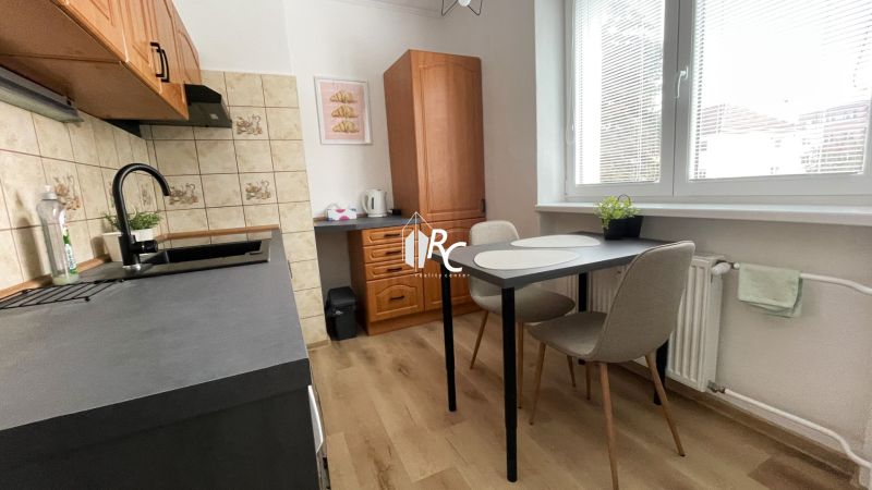 Prenájom 2-izbový byt s balkónom Martin – Podháj (41m2) - Kuchyňa v 2-izbovom byte s podlahou s dreveným dekorom a jedálenským stolom.