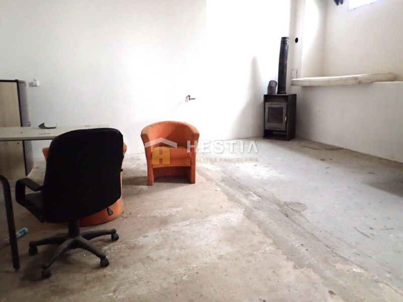 Hala na prenájom 400 m2 – priemyselná zóna - Priestor so starými sedačkami, stolom a kozubom vo výrobných priestoroch.