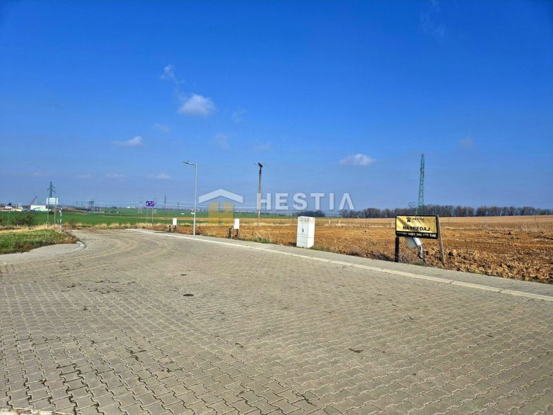 Stavebné pozemky 614 m² v novo-vybudovanej lokalite Hlboké - Spevnená cesta vedúca k pozemkom na bývanie v Hlbokom, s jasnou oblohou.