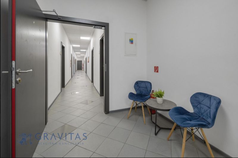 Kancelárie na PRENÁJOM | Vajnorská | TOP lokalita - Kancelárie s chodbou, modrými stoličkami a stolom, podlaha s dlažbou.