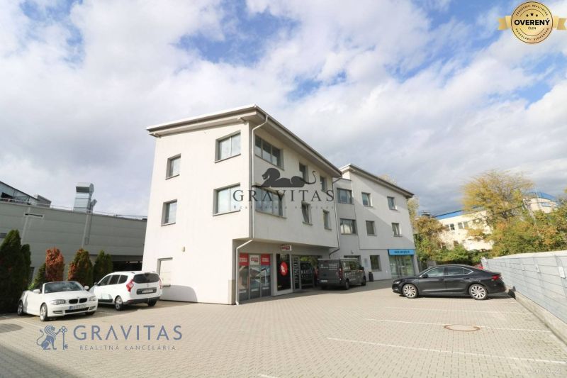 Samostatná kancelária 19,16 m2 - Lamačská cesta - Budova na ulici Lamačská cesta so zaparkovanými autami, kancelárie na prízemí, oblačné nebo.