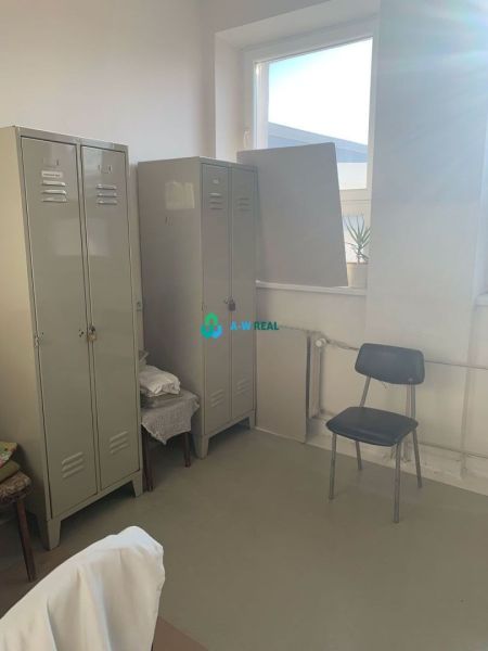 Výrobné a skladové priestory na prenájom. - Skrinky, stolička, radiátor a okno vo výrobných priestoroch s podlahou s dreveným dekorom.