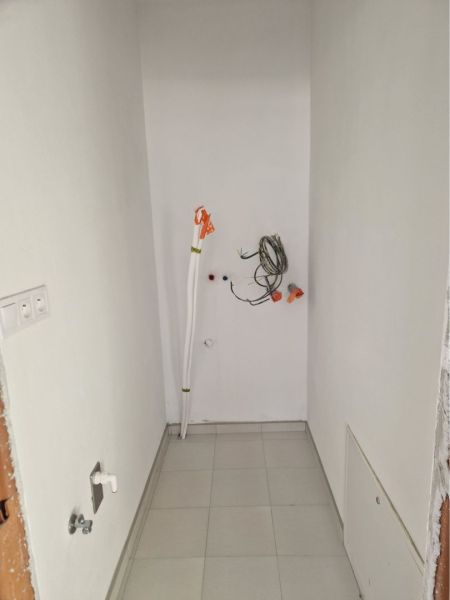 NOVOSTAVBA! 3- izbový byt so záhradkou - Úzky priestor v 3-izbovom byte s bielymi stenami a keramikou pod nohami.