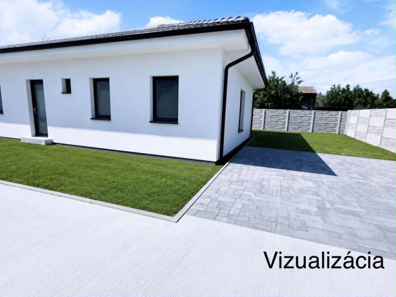 Už toto leto vo Vlastnom s tepelným čerpadlom v cene - Rodinný dom v Padáni na fotografii s bielou fasádou a zatrávneným dvorom.