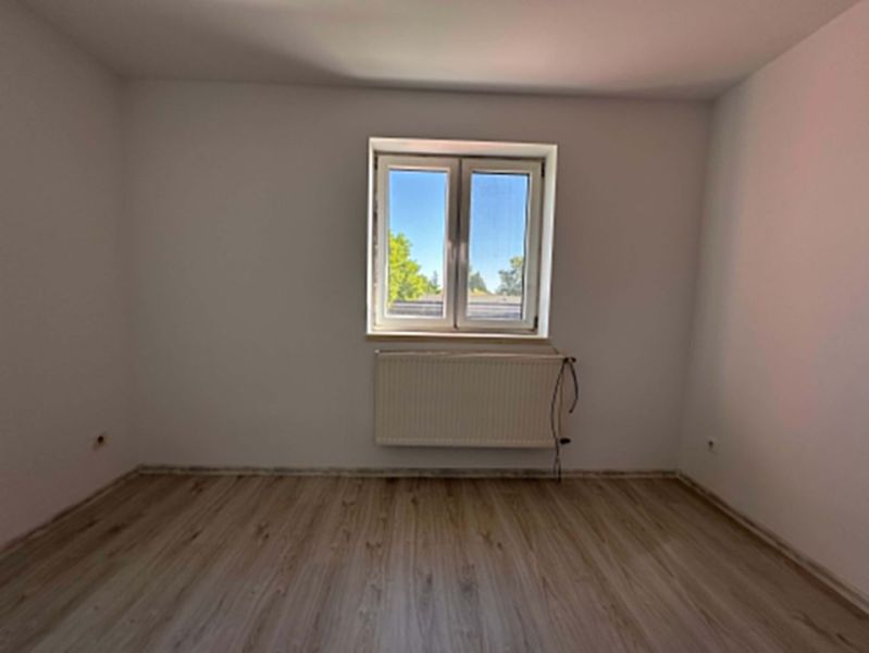 ☎️ 0918/197 701 NA PREDAJ 3-izbový byt v Lehniciach s vlastným kúrením - Izba v 3-izbovom byte s podlahou s dreveným dekorom, bielymi stenami a veľkým oknom.