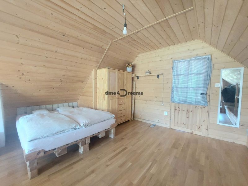 NA PREDAJ Čarovný vidiecky dom s kachľovou pecou NEMECKÁ - Drevený interiér s posteľou na paletách, skriňa a podlaha s dreveným dekorom.