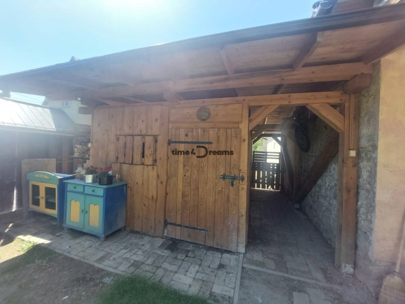 NA PREDAJ Čarovný vidiecky dom s kachľovou pecou NEMECKÁ - Drevený prístrešok pri rodinnom dome v Nemeckej, vybavený farebnými skrinkami.