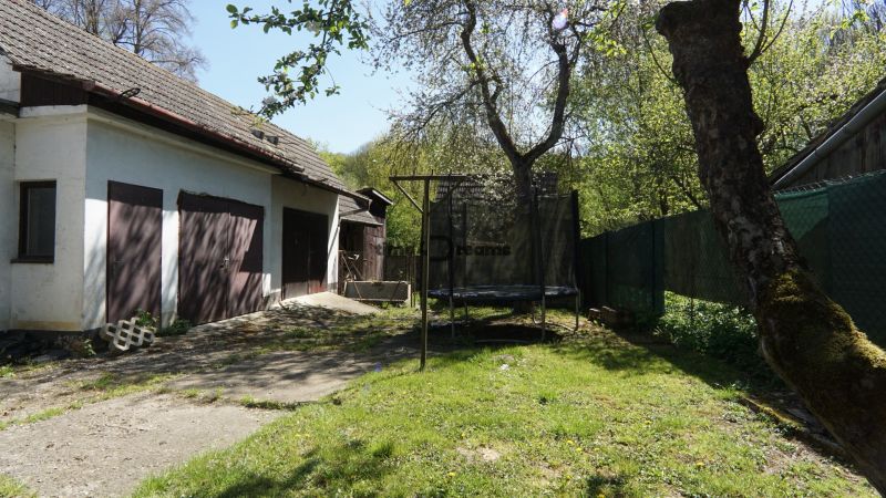 NA PREDAJ – chalupa alebo rodinný dom na pokojné bývanie  - Rodinný dom v Krajnom s garážou, záhradou, stromami a trampolínou na tráve.